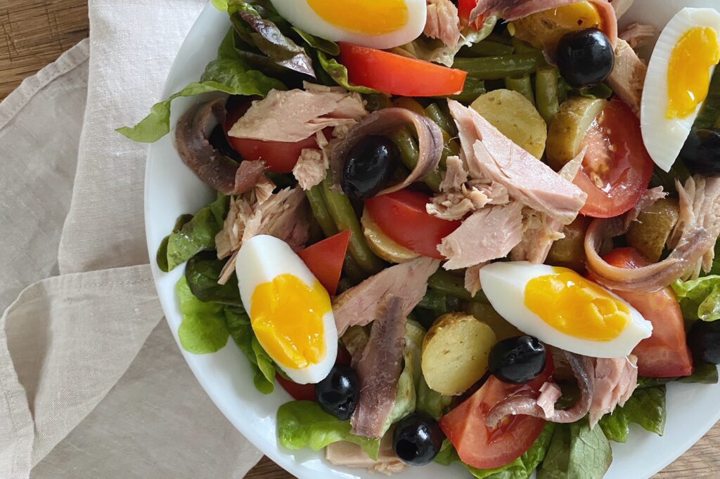 Salade Niçoise mit Sardellen, Thon, Eiern und Oliven in einer weissen Schüssel serviert
