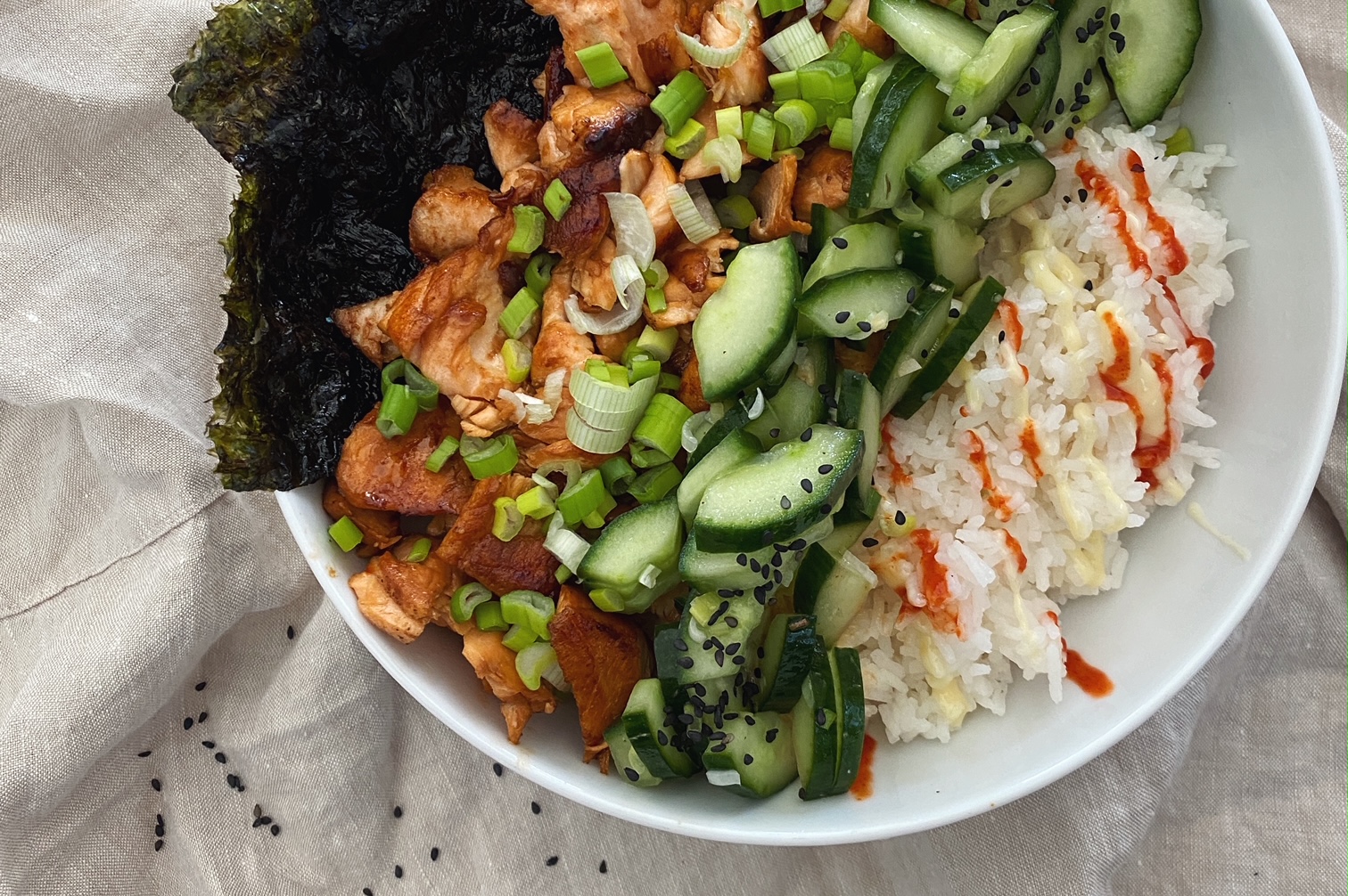 Lachs-Bowl mit Reis und Gurkensalat - von oben fotografiert auf einer beigen Leinentischdecke